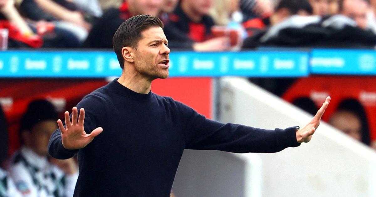 Huấn luyện viên tại Bundesliga đang tận tình hướng dẫn kỹ thuật cho một nhóm cầu thủ trẻ trên sân tập câu lạc bộ.